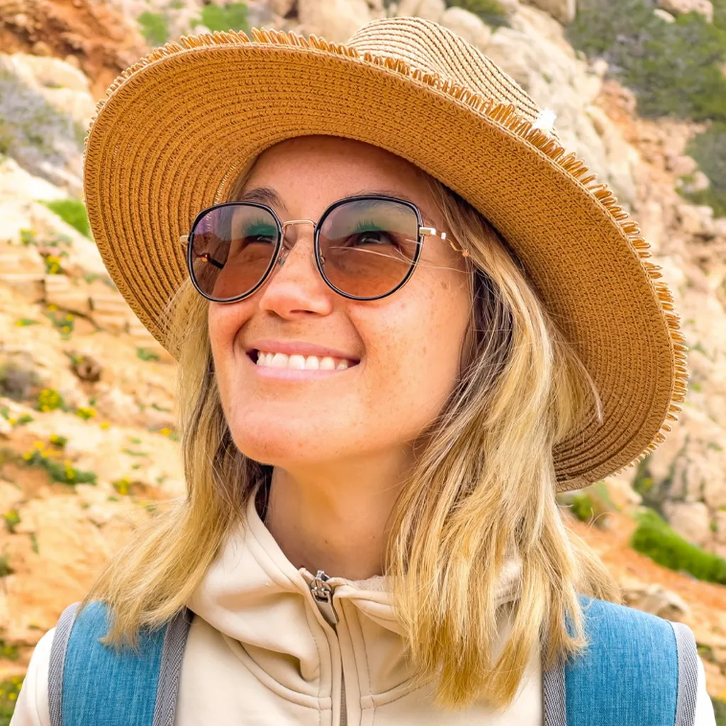 Sarah Janßen mit Sonnenhut und Sonnenbrille lächelt vor felsiger Landschaft